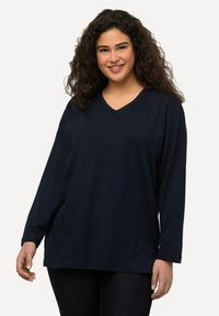 Marineblaue Langarm-V-Ausschnitt-Bluse aus weicher Baumwolle, mit lockerem Schnitt und glatter Textur, ohne sichtbare Muster oder Beschläge.