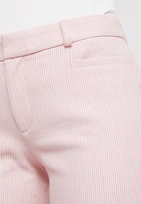 Light pink striped pants with a smooth texture, featuring a standard waistband, subtle back pocket, and vertical pinstripes.