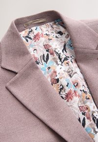 Lyse lilla blazer med en tekstureret yderside og blomstret foer i pastel farver, med en hakket krave og skulderpuder.