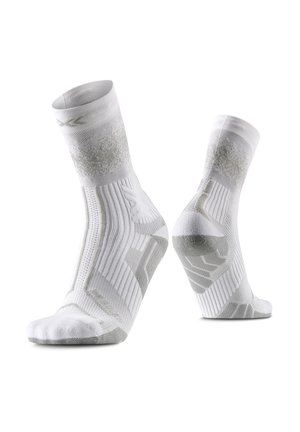 Een paar witte sportsokken met gestructureerde boog- en hielondersteuning, getoond op onzichtbare voetvormen tegen een witte achtergrond.