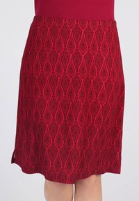 Roter knie-langer Rock mit einem strukturierten Muster aus Paisley-Formen. Glattes Material mit seitlichen Schlitzen, die eine fließende Silhouette erzeugen.