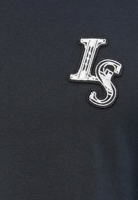 Dark blue cotton t-shirt featuring a white embroidered "LS" logo on the left side, with a textured ribbed fabric.