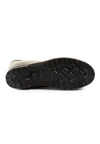 Semelle de chaussure en caoutchouc noir avec un motif de semelle pour une meilleure traction. Le design inclut des rainures et des sections surélevées pour un grip amélioré.