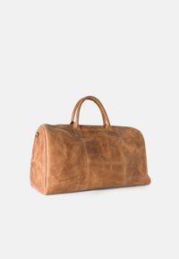 Tan leather duffel bag with smooth texture, rounded shape, two top handles, and metal accents. Features stitched panels for design detail.