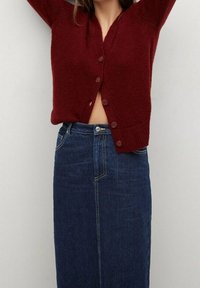 Burgundin värinen neulecardigan, jossa on V-pääntie ja napit edessä, yhdistettynä korkea vyötäröinen farkkuhame, jossa on etusauma.