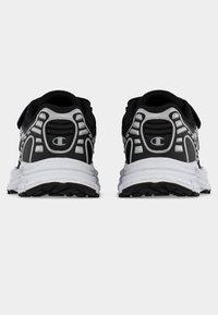 Chaussures de sport noires et blanches avec une semelle texturée, dotées d'un col de talon rembourré, de panneaux en mesh et d'accents de logo contrastants et visibles.