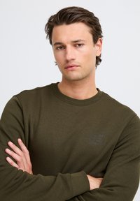 Olijfgroene sweatshirt van katoenmix, met een geribbelde ronde hals en een klein gedrukt logo op de linkerkant van de borst.