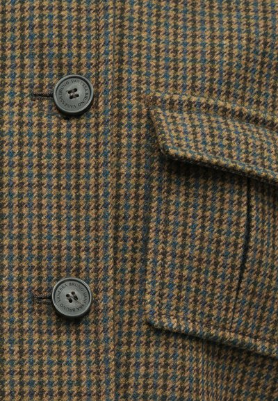 Brązowo-zielona tkanina w wzór houndstooth, z ciemnymi guzikami, klapką kieszeni oraz teksturalnymi detalami powierzchni.