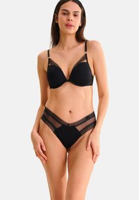 Ensemble de lingerie noir comprenant un soutien-gorge rembourré avec des bordures en dentelle et un brief taille haute avec des panneaux en tulle et des détails en dentelle contrastante.