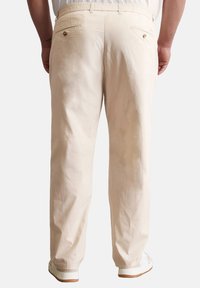 Beige katoenen broek met een ontspannen pasvorm, een elastische tailleband en twee achterzakken met accenten in goudkleurige hardware.