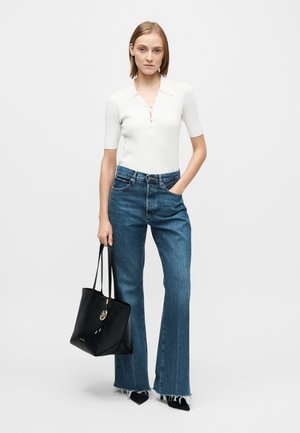 White ribbed short-sleeve top with a collar, paired with high-waisted, flared blue jeans featuring frayed hems, and a black tote bag.