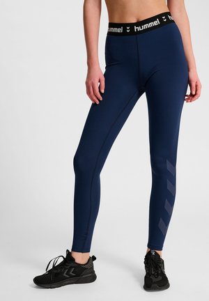 Marineblauwe sportleggings met een zwarte elastische tailleband met het "hummel"-logo; slanke pasvorm en subtiel chevronpatroon aan de zijkant.