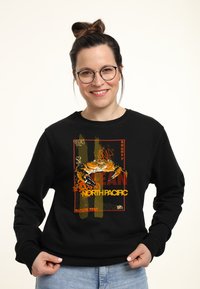 Felpa nera con una grafica di un granchio e il testo "NORTH PACIFIC" in arancione e giallo, su uno sfondo testurizzato in colori tenui.