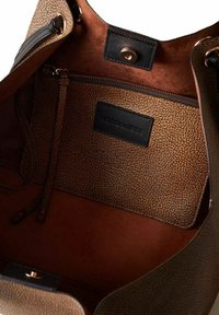 Interno di una borsa in pelle marrone con una pochette marrone chiaro testurizzata dotata di cerniera. La fodera è liscia e di un marrone più scuro. Etichetta del marchio visibile.