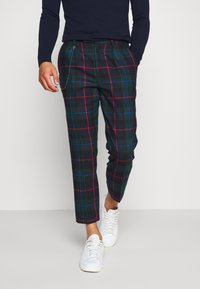 Czarna w kratę spodnie w ciemnozielonym kolorze z czerwono-niebieskim wzorem, o slim fit i bocznymi kieszeniami; uzupełnione łańcuchem.