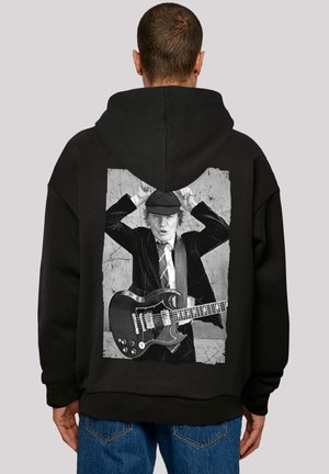 Black hoodie featuring a large graphic of a musician holding a guitar, printed in grayscale. The design includes a textured background.