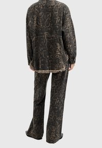 Chaqueta oversized de estampado animal en negro y marrón y pantalones a juego, con un dobladillo deshilachado, un ajuste relajado y un material texturizado.
