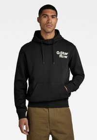 Schwarzer Hoodie mit einer Kängurutasche und verstellbarem Kapuzenzug. Mit dem G-Star Raw Logo in Hellgrau auf der Brust. Gerippte Bündchen und Saum.