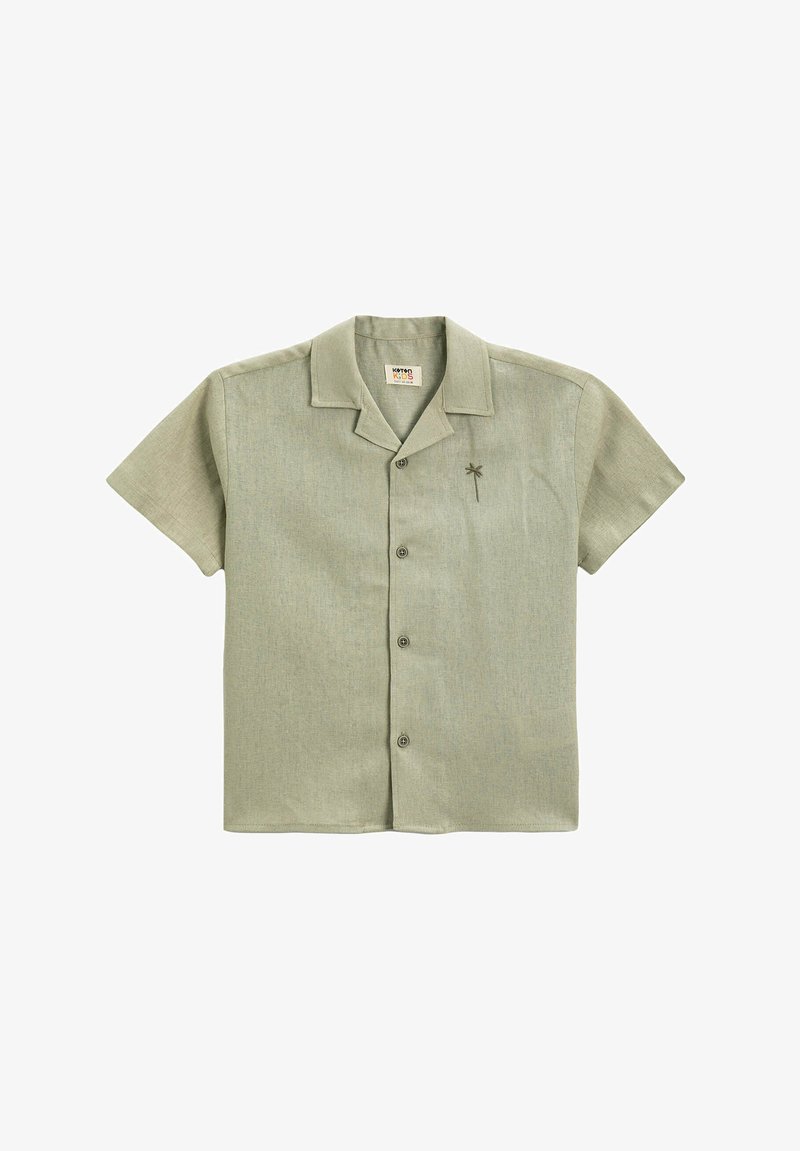 Camisa de manga corta, abotonada, en tela verde clara con una ligera textura. Presenta un collar y un pequeño bordado de una palmera.