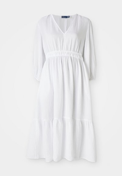 Robe blanche avec un décolleté en V, taille élastique et manches trois-quarts. Elle présente un ourlet à volants en couches et un tissu texturé.