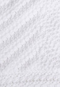 Witte gebreide deken met een gestructureerd zigzagpatroon, met een zachte, fluffy weving en een nette afgebouwde rand. Ideaal voor warmte en comfort.