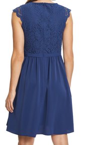 Marineblå kjole med blonder på overdelen og et flydende chiffon-nederdel. Fine kappersærmer og en skjult lynlås bagpå til lukning.