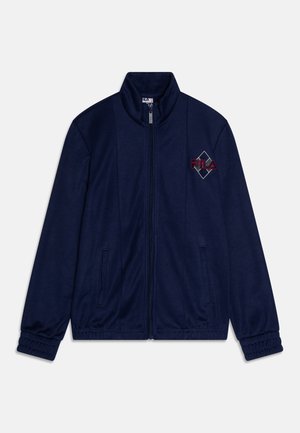 Veste zippée marine avec col haut, poignets élastiques et deux poches latérales. Présente le logo Fila brodé en forme de losange sur la poitrine gauche.