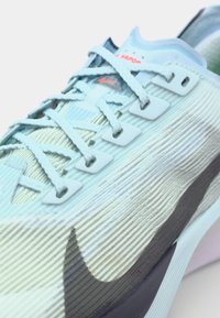 Baskets de course bleu clair avec une tige texturée, des accents gris, des œillets blancs et des lacets ronds. Présente un design courbé pour une performance améliorée.