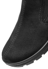 Nahaufnahme von der Vorderseite eines schwarzen Wildlederstiefels mit sichtbarer Naht und strukturiertem Gummisohlenprofil.