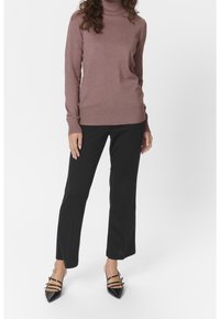 Gebreide coltrui in mauve, met geribbelde mouwen en onderrand. Zwarte taillepants met een rechte snit. Puntige zwarte hakken met bandaccenten.