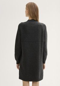 Abito maglione grigio scuro con texture a coste, maniche lunghe e orlo leggermente svasato. Il design sul retro presenta un pannello a blocchi di colore.