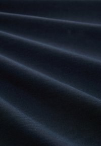 Marineblaue Stoff mit einer glatten, matten Textur und einem dezenten gerippten Muster, das weiche Falten und eine einheitliche Farbe aufweist.