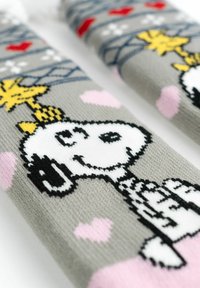 Gray knitted socks featuring a cartoon dog design, black outline, white face, and yellow star. Accents in pink hearts and blue pattern.