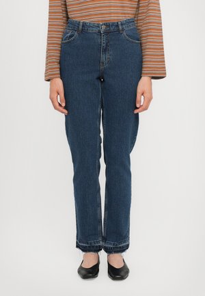 Dark blue, straight-leg jeans with a faded texture, high waist, and frayed hem, complemented by black flat shoes.