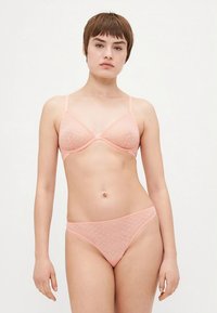 Roze lingerieset met licht gewatteerde, driehoekige beha en bijpassende string. Beiden hebben een gestructureerd patroon met kleine stippen.