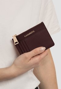 Portafoglio in pelle bordeaux con finitura testurizzata, hardware dorato e logo impressa; presenta più scomparti per carte e una tasca con zip.