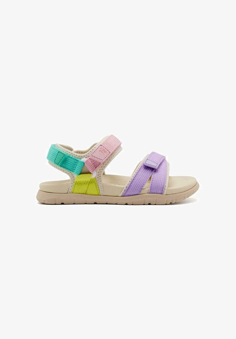 Sandalias infantiles coloridas con correas ajustables de Velcro en verde, rosa, amarillo y morado. Presentan una suela de goma beige y un tejido texturizado.