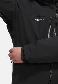 Black Mammut jacket featuring a zippered front, elastic cuffs, and a zippered chest pocket with a smooth fabric texture.