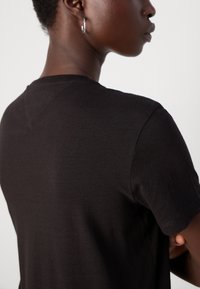 Svart bomull T-skjorte med korte ermer, med rund halslinning og subtile sømdetaljer på skulderen. Enkel og klassisk design.