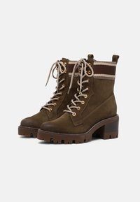 Braune Wildleder-Stiefeletten mit einem dicken Absatz, Schnürdesign, goldenen Ösen und einem gestreiften Stoffakzent an der Oberseite. Texturierte Sohle.