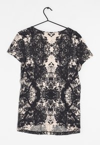 Korte mouw t-shirt met een zwart boompatroon op een licht crème achtergrond. Zachte stof met een ronde halslijn en een gebogen zoom.