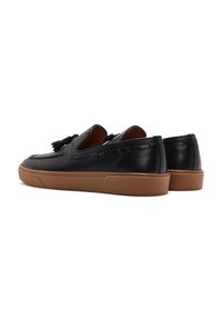 Scarpe slip-on nere in pelle con finitura testurizzata, suola in gomma marrone e un nappino decorativo sulla parte superiore.