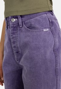 Shorts di jeans viola con cuciture visibili e un piccolo cartellino "ELEMENT". Presentano una chiusura frontale a bottone e tasche laterali. Texture morbida.