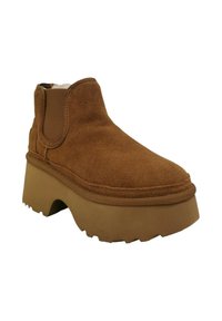 Stivale alla caviglia in suede marrone con superficie testurizzata, pannelli laterali elasticizzati e una suola platform beige spessa con fondo a traccia.