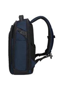 Zaino blu navy e nero con spallacci imbottiti, numerosi scompartimenti con zip e tasche laterali in rete, mostrato di lato su sfondo bianco.