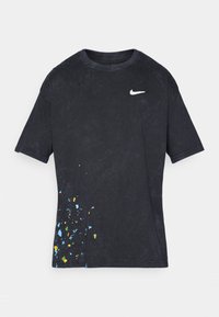 Sort bomulds t-shirt med rund hals, prydet med et hvidt Nike-logo og et farverigt splattermønster på den nederste venstre side.