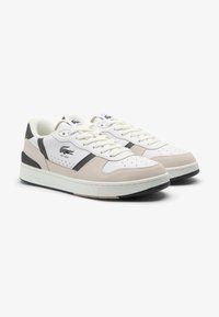 Sneaker bianco in pelle e scamosciato beige con finitura testurizzata, punta tonda, design stringato e logo del marchio a contrasto sul lato.
