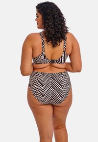 Musta ja kermanvalkoinen raidoitettu bikinit, joissa on kevyet chevron-kuviot. Säädettävät olkaimet, korkea vyötärö ja sileä kangas.