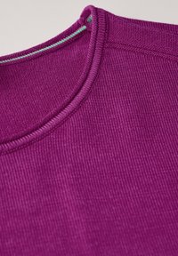 Tissu texturé fuchsia avec un design à côtes, doté d'un col rond et de surpiqures vertes contrastantes le long du col.