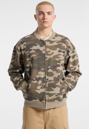 Camo bomberjack in tinten van groen en bruin. Beschikt over een voorrits, geribde manchetten en zijzakken. Zacht, textuurstof.